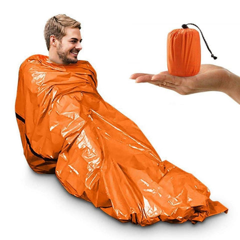 Man in orange emergency bivy and picture for scale of bivy stored an compact bag